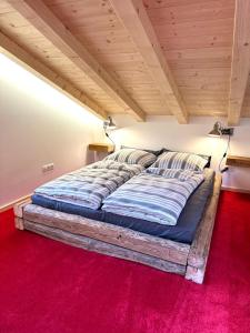Cama grande en habitación con alfombra roja en DIE ZWEI CHALETS AM TEGERNSEE "s' Gloane" & "s' Große", en Rottach-Egern