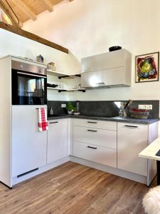 a kitchen with white cabinets and a stove at DIE ZWEI CHALETS AM TEGERNSEE "s' Gloane" & "s' Große" in Rottach-Egern +21 photos