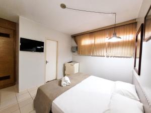 1 dormitorio con 1 cama blanca y TV en Hotel Alvorada Taguatinga - Antigo Hotel Atlantico, en Taguatinga