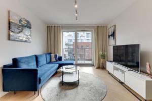 een woonkamer met een blauwe bank en een tv bij Apartament nad Motławą - Gdańsk! in Gdańsk