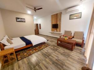 a bedroom with a bed and a couch and a tv at Grand Narmada Homestay Resort-Bandhavgarh in Tāla