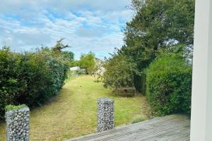 vistas a un patio con árboles y una terraza de madera en Cottage Arlette à 600m de la mer en Cayeux-sur-Mer