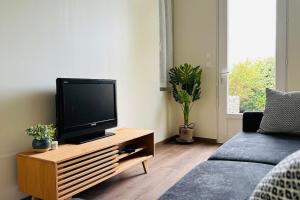 uma sala de estar com uma televisão de ecrã plano numa mesa de madeira em Cottage Arlette à 600m de la mer em Cayeux-sur-Mer