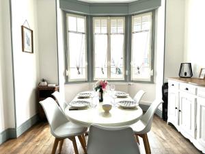 uma mesa de jantar com cadeiras brancas e uma mesa branca em Cottage Arlette à 600m de la mer em Cayeux-sur-Mer