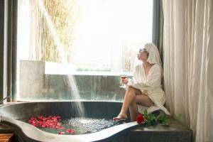 a woman sitting in a bath tub with a glass of wine at Palm View Villa in Hoi An