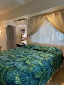 a bedroom with a bed with a blue and green bedspread at Kalama Room in Kailua