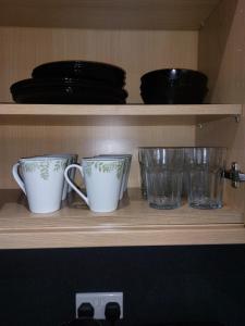 three cups and glasses sitting on a shelf at 2 large bedroom apartment- WIFI & Parking in Fleetwood