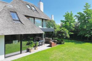 une maison avec un toit de chaume et une cour dans l'établissement high end luxury villa near Royal Knokke Golf, à Knokke-Heist