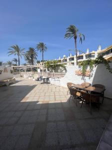 a patio with a table and chairs and palm trees at San Agustin apartments , close to the BEACH, with pool! in San Bartolomé