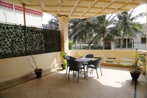 un patio con mesa, sillas y palmeras en Waypoint Hotel en Karachi