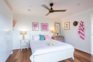 a bedroom with a white bed with a ceiling fan at Bimbajong Studio - oceanstays in Yamba