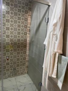 uma casa de banho com um chuveiro e toalhas brancas em Bel appart said hajji em Salé