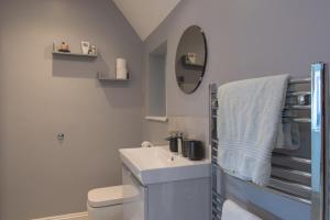 a bathroom with a sink and a toilet and a mirror at 6 Bedroom Holiday Home with Hot Tub & Garden in Luton