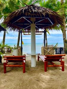 dwie ławki siedzące pod parasolem na plaży w obiekcie Treasure Beach Resort w mieście Carles