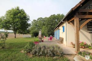 a house with a porch with chairs and a yard at Les Volets Bleus in Dornes +4 photos