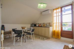 a kitchen with a table and chairs and a window at Les Volets Bleus in Dornes