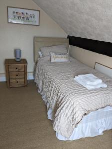 a bedroom with a bed and a wooden night stand at The Carmen Guesthouse in Llandudno