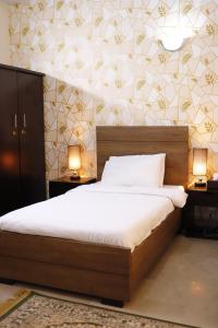 a bedroom with a bed and two night stands and two lamps at Waypoint Hotel in Karachi