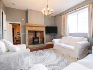 a living room with two white couches and a fireplace at The Cottage in Belper