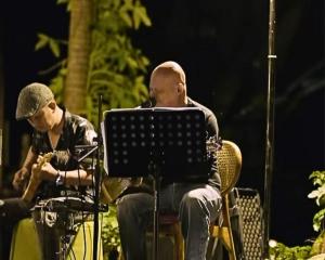 a man sitting in a chair next to a man playing guitar at Menzel Ubud in Ubud