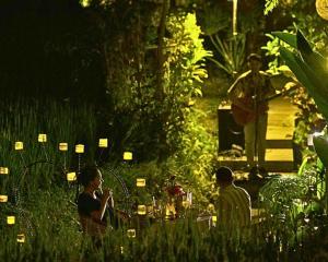 a group of people in a garden at night at Menzel Ubud in Ubud