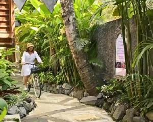 a woman riding a bike through a garden at Menzel Ubud in Ubud