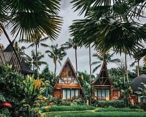 a house with palm trees in front of it at Menzel Ubud in Ubud