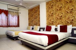 a bedroom with two beds with red and white pillows at Hotel Satluj in Ahmedabad