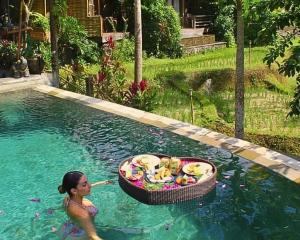 a woman in a swimming pool with a basket of food at Menzel Ubud in Ubud