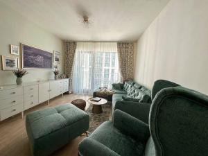 ein Wohnzimmer mit einem grünen Sofa und Stühlen in der Unterkunft SuprStay - Belgrade Waterfront Luxury Apartment in Belgrad
