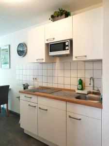 eine Küche mit weißen Schränken, einer Spüle und einer Mikrowelle in der Unterkunft Alissa in Ludwigsburg