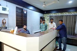 a group of men standing at a counter in an office at Hotel Satluj in Ahmedabad