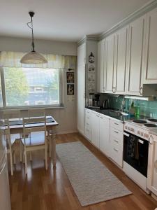 a kitchen with white cabinets and a table and a window at Apartment Puistokatu in Kokkola