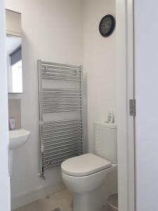 een witte badkamer met een toilet en een klok aan de muur bij Barnoaks House - New Private Room with Private Bathroom in Dublin
