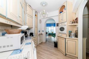 uma cozinha com armários brancos e um micro-ondas branco em Residence Les Voiles Blanches - Postcard view on the Croisette em Cannes