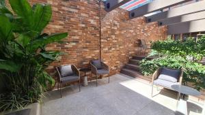 un patio con 3 sillas y una pared de ladrillo en TrevizZo Haddock Lobo, en São Paulo