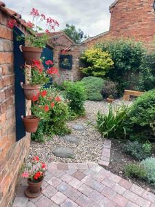 a garden with flower pots on a brick wall at The Hideaway at Peacock Farm in Bottesford