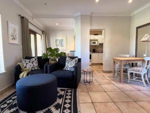 Una sala de estar con un sofá azul y una mesa. en Kwendalo, en Plettenberg Bay