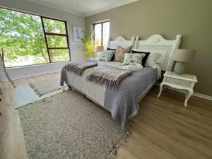 a bedroom with a large bed with a large window at Kwendalo in Plettenberg Bay