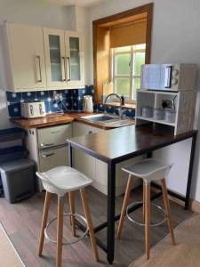 a kitchen with a counter and two stools in it at The Hideaway at Peacock Farm in Bottesford