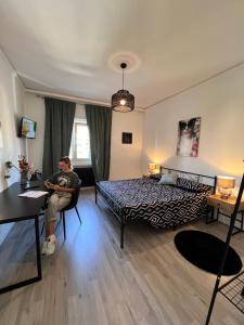 un homme assis sur une chaise dans une chambre dans l'établissement Appartamento con vista mare e parcheggio, à Trieste