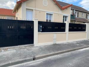 une maison avec une clôture et un portail noir dans l'établissement Maison Goussainville - Aéroport ROISSY CHARLES DE GAULLES & PARIS, à Goussainville