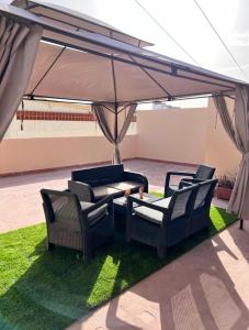 a patio with two chairs and a table under a canopy at Apartamento Los Girasoles in Corralejo