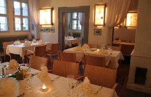 Pörtnerhof Seßlach في Seßlach: مطعم بطاولات بيضاء وكراسي ونوافذ