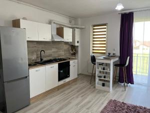 una cucina con armadi bianchi, lavandino e frigorifero di Premium Apartament a Giroc