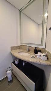 a bathroom with a sink and a large mirror at TrevizZo São Caetano do Sul in São Caetano do Sul