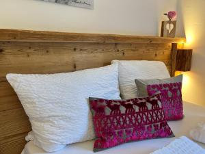 a bed with white and pink pillows on it at Alpflower in Halblech