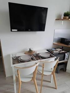 een tafel met twee stoelen en een televisie aan de muur bij Le Kinfolk studio in Châtel-Guyon