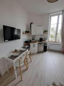 een witte keuken met een tafel en een fornuis bij Le Kinfolk studio in Châtel-Guyon
