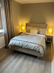 1 dormitorio con 1 cama con 2 lámparas en 2 mesas en Sarah’s cottage, en Newry